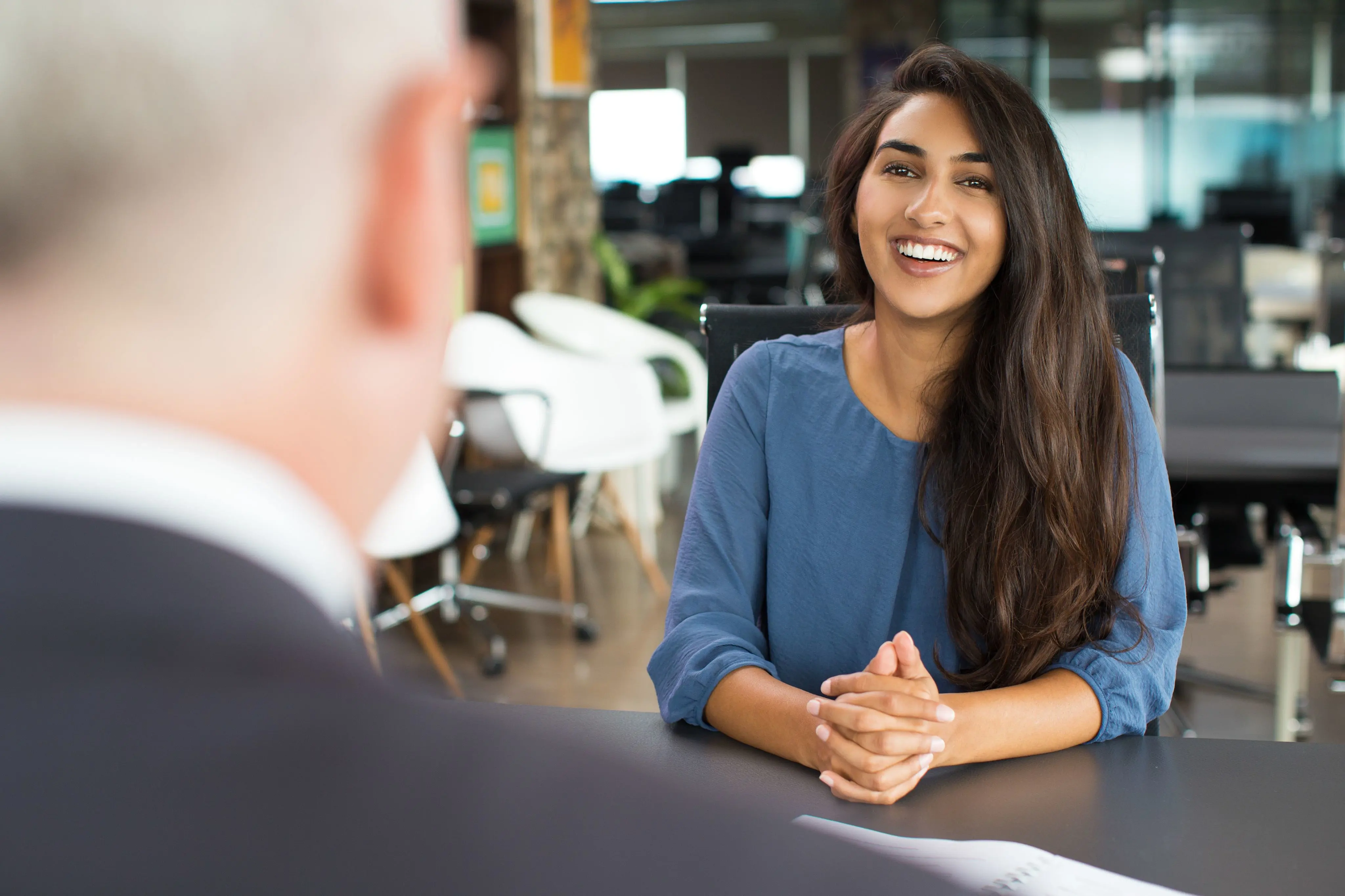 Two people in a business meeting, young women with hands clasped on a table.